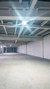Interior de una minibodega de techo alto con lámparas LED encendidas y piso de alta resistencia.