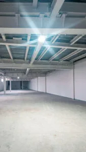 Interior de una minibodega de techo alto con lámparas LED encendidas y piso de alta resistencia.