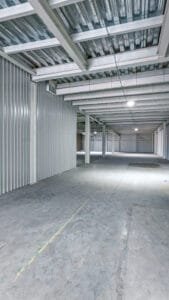 Pasillo interior amplio y bien iluminado de un módulo de minibodegas industriales vacías.