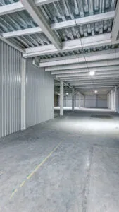 Pasillo interior amplio y bien iluminado de un módulo de minibodegas industriales vacías.