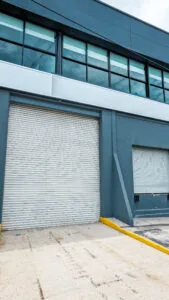 Fachada de una minibodega industrial con una gran cortina metálica enrollable de color blanco.