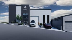 Render exterior de una nave industrial con diseño contemporáneo, mostrando su área de oficinas de dos pisos y el acceso a la bodega.