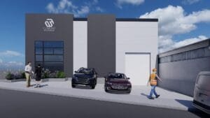 Render exterior de una nave industrial con diseño contemporáneo, mostrando su área de oficinas y el acceso a la bodega.